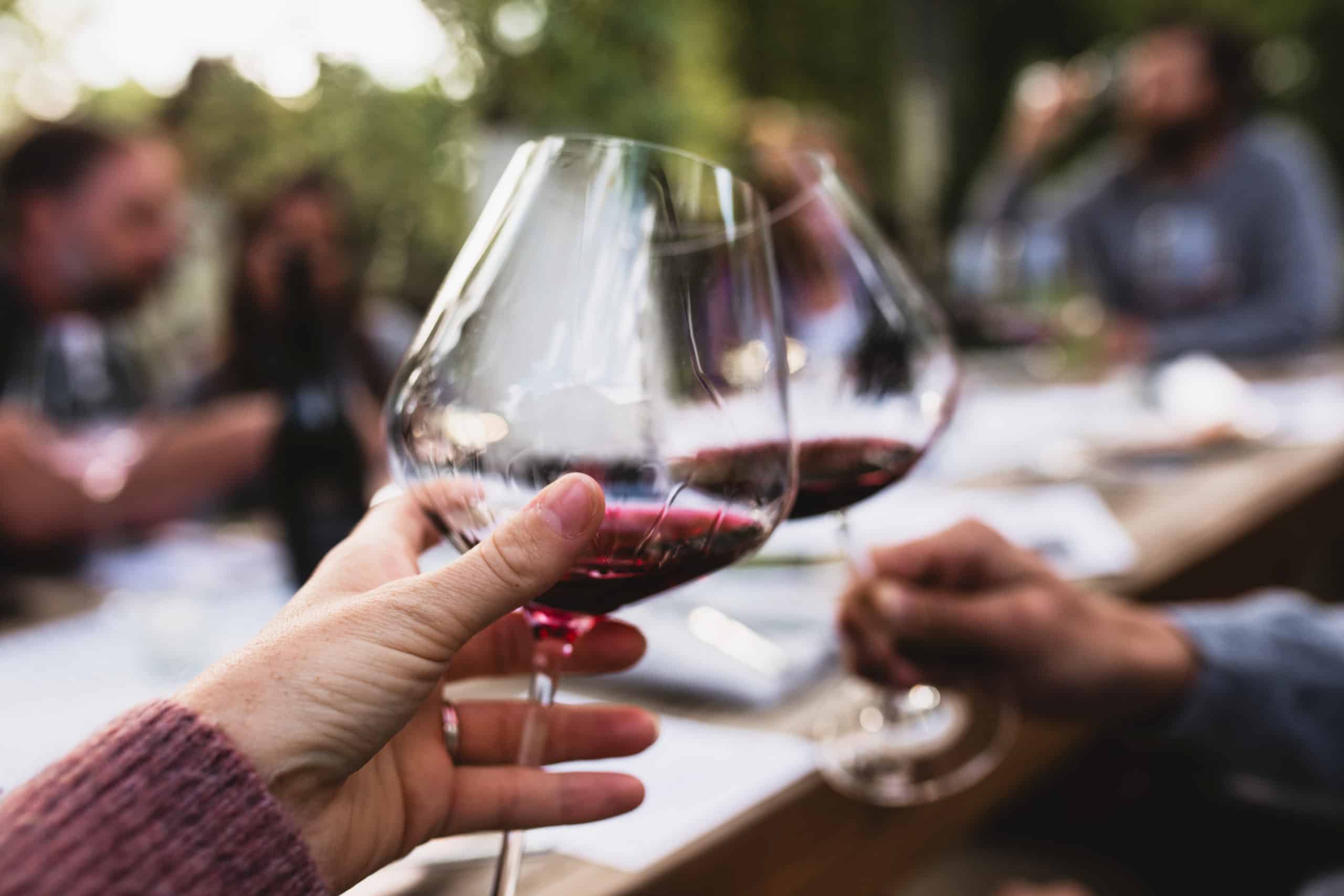 hand holding wineglass toasting glass with another person