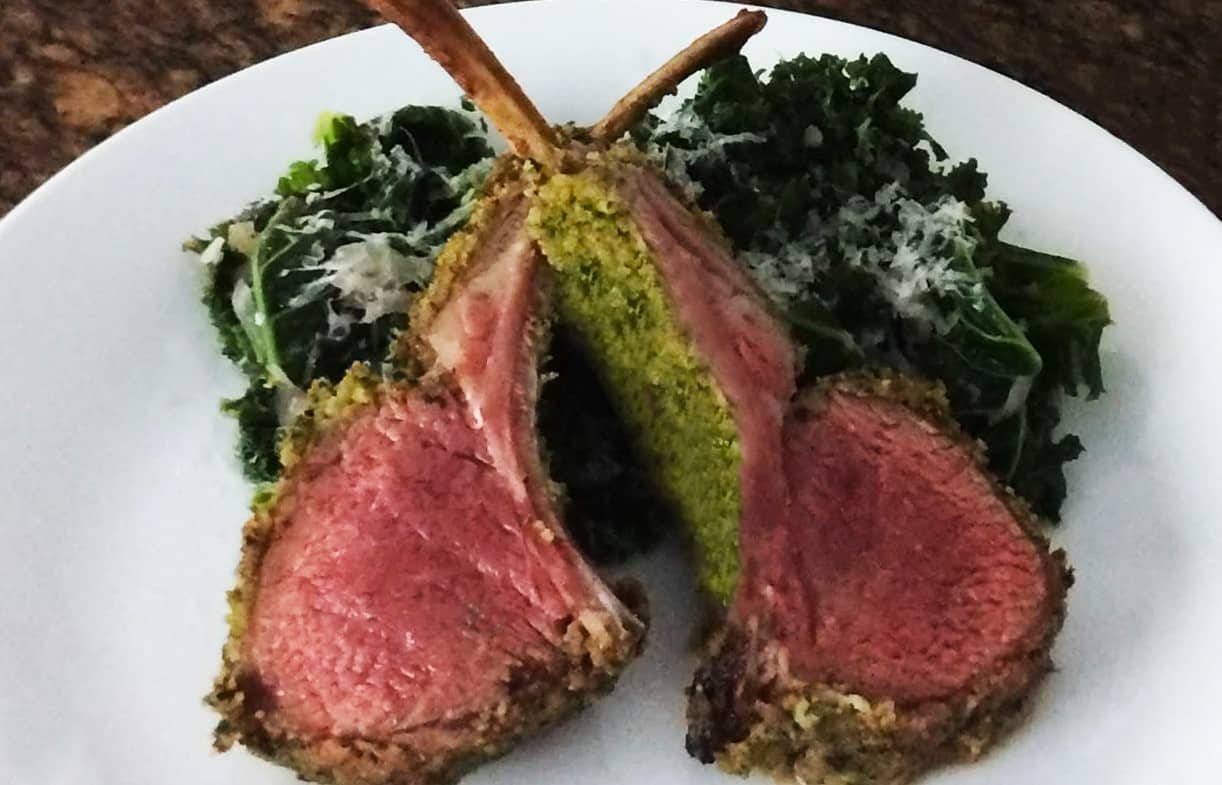 Lamb rack dish served with kale salad topped with shaved cheese plated on white plate